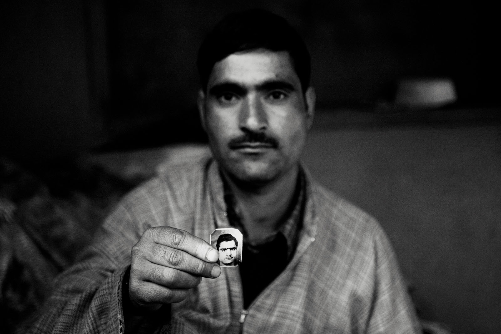 A man shows the picture of his missing brother, in north Kashmir